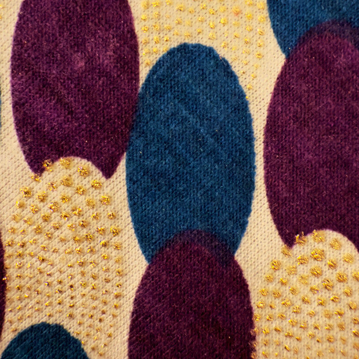 Close-up of a textured fabric with purple, blue, and gold pattern