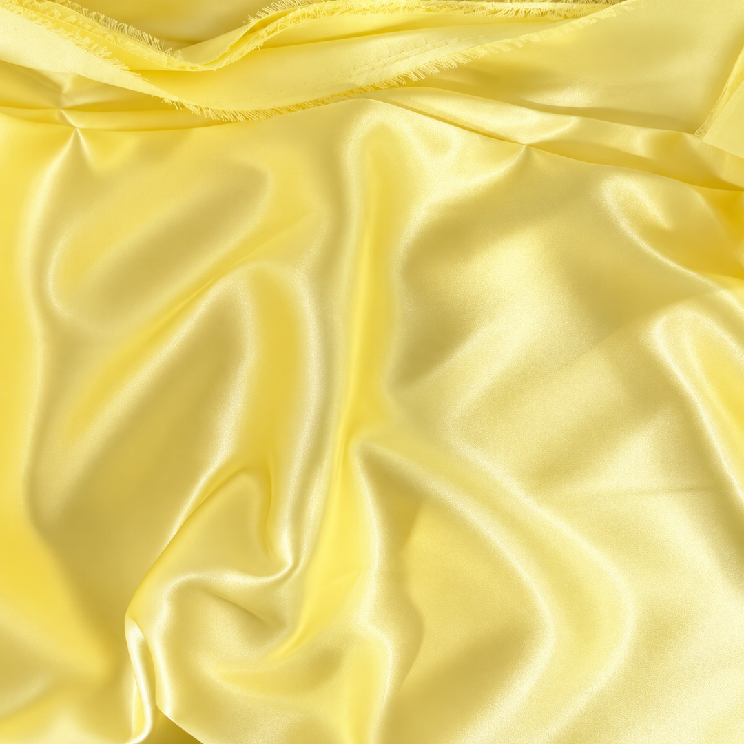 Yellow satin fabric with a soft, lustrous sheen and elegant draped folds.