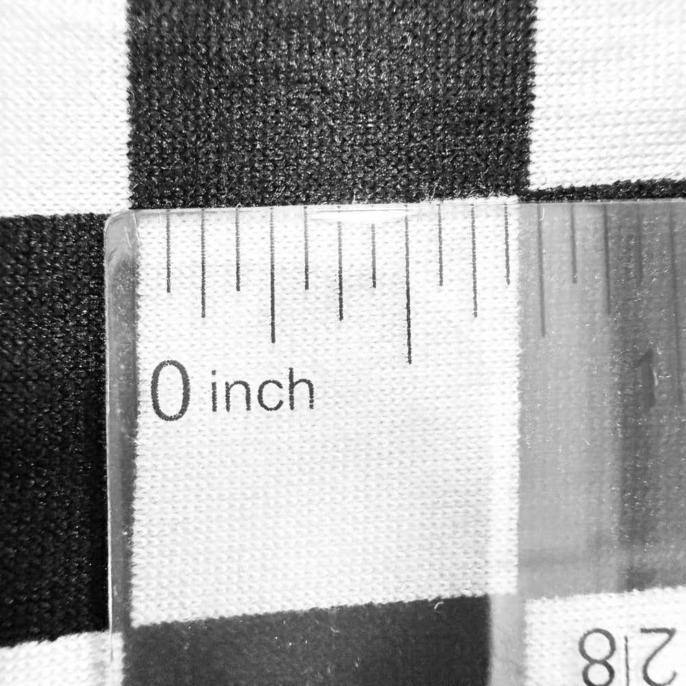 Close-up of black and white checkered fabric with a ruler measuring 0 inches, showcasing the texture and pattern.