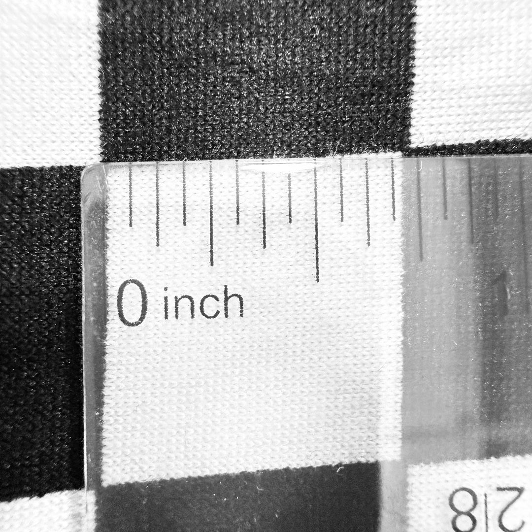 Close-up of black and white checkered fabric with a ruler measuring 0 inches, showcasing the texture and pattern.