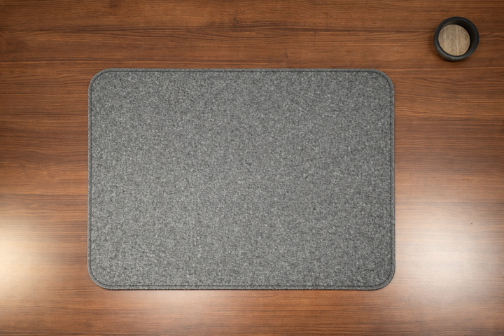 Gray surface protector on a wooden floor with a small black container for wires.