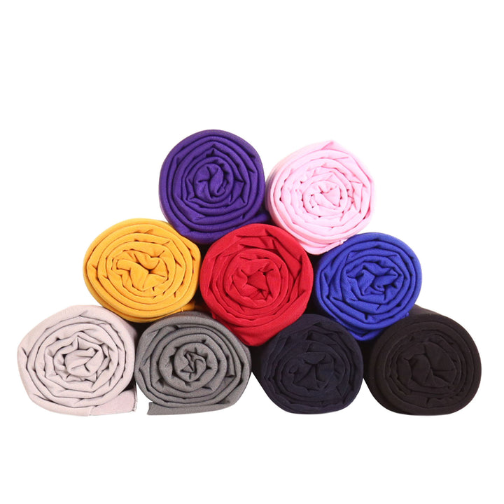 Various rolled ITY Polyester Spandex fabrics in vibrant colors including yellow, purple, pink, red, and black.