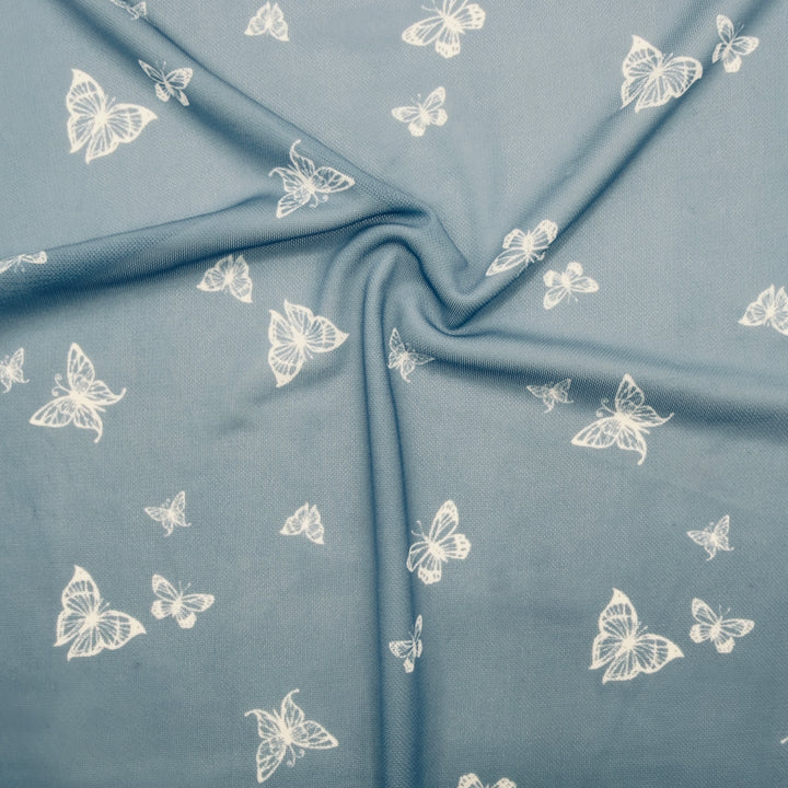 Nylon spandex fabric featuring a chambray butterfly pattern on soft blue background, ideal for stylish garments.