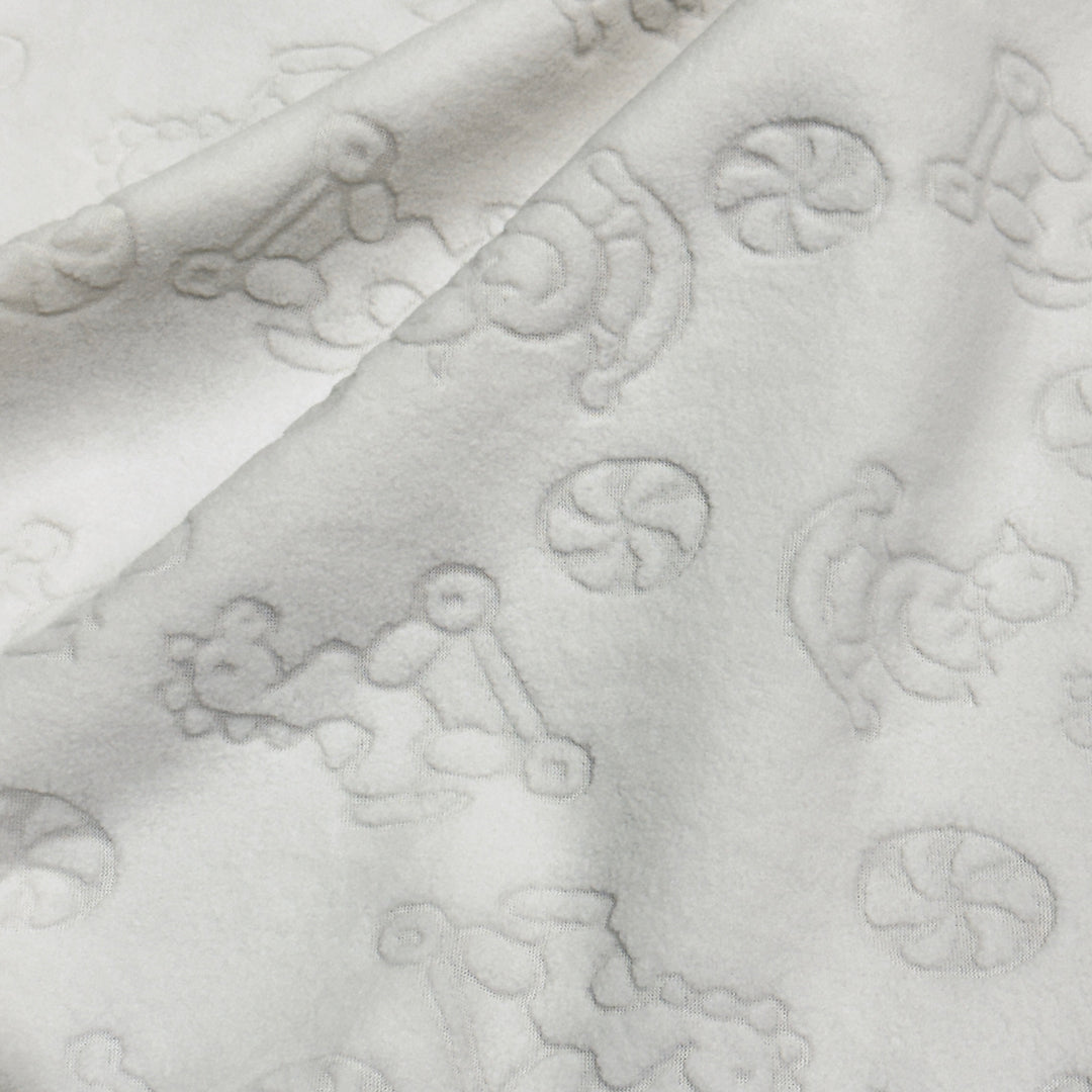 Ivory embossed anti-pill polar fleece with raised baby toy pattern, draped
