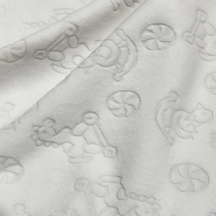 Ivory embossed anti-pill polar fleece with raised baby toy pattern, draped